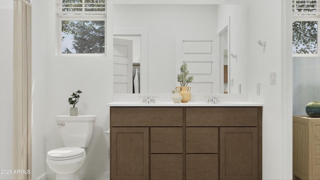 bathroom with toilet, plenty of natural light, double vanity, and a sink