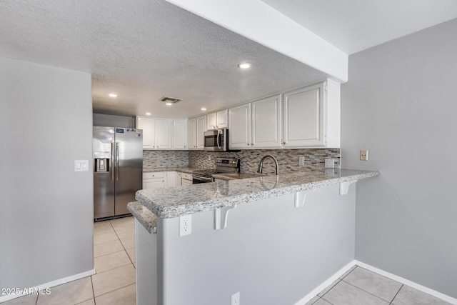 11217 E Laurel Ln, Scottsdale, AZ 85259 - kitchen featuring stainless steel appliances, light tile patterned floors, a peninsula, decorative backsplash, and a breakfast bar area
