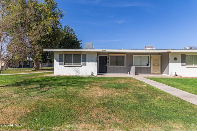 ranch-style home featuring a front yard and concrete block siding