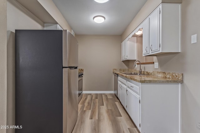 kitchen featuring light wood-type flooring, white cabinetry, appliances with stainless steel finishes, and a sink