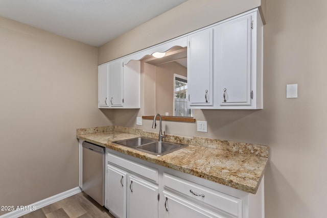 kitchen with baseboards, white cabinets, dishwasher, light countertops, and a sink