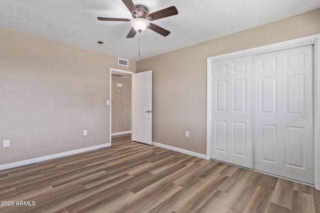 unfurnished bedroom with a closet, visible vents, baseboards, and wood finished floors