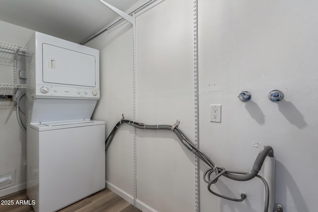 laundry room featuring laundry area, visible vents, stacked washer / dryer, and wood finished floors