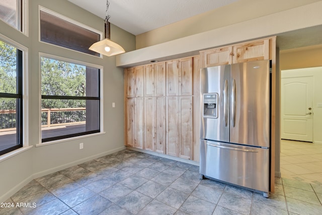 kitchen featuring light tile patterned flooring, stainless steel refrigerator with ice dispenser, decorative light fixtures, and light brown cabinetry