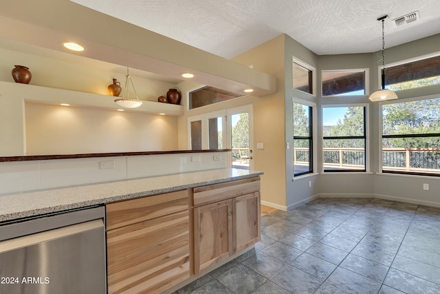 kitchen featuring a wealth of natural light, a textured ceiling, light brown cabinetry, and decorative light fixtures