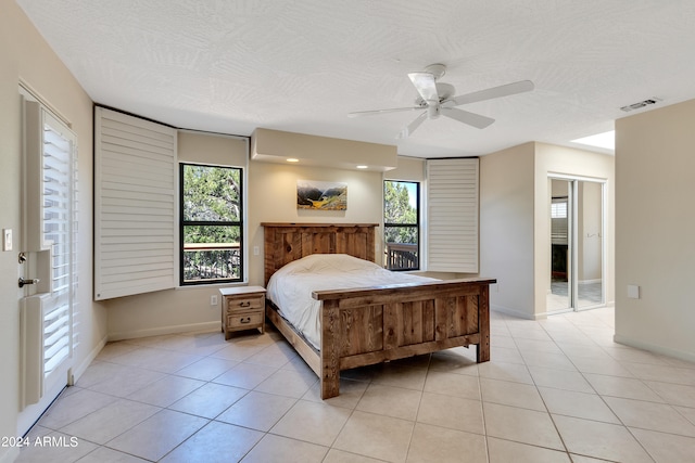 bedroom with multiple windows, a textured ceiling, light tile patterned floors, and ceiling fan