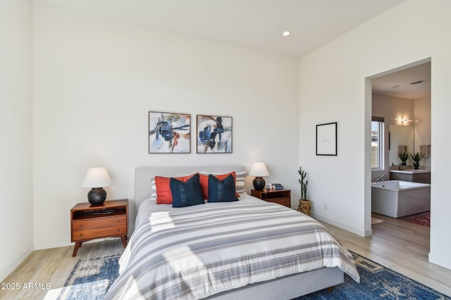 bedroom featuring connected bathroom and light wood-type flooring