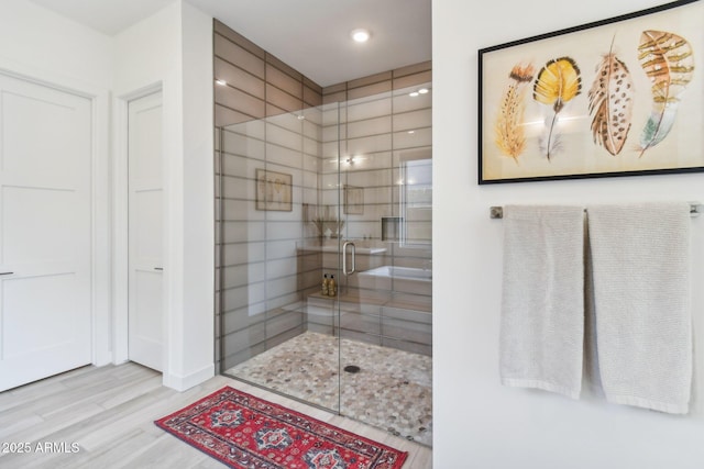 bathroom with a shower with door and wood-type flooring