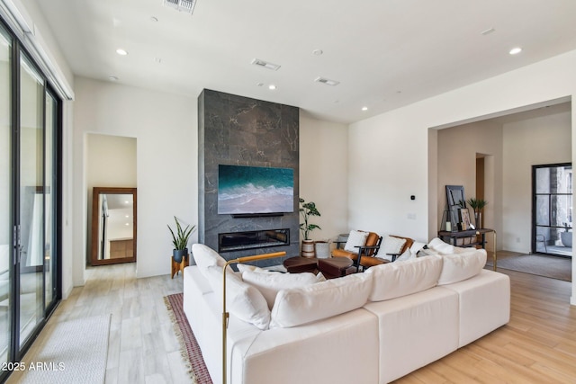 living room featuring a high end fireplace and light wood-type flooring