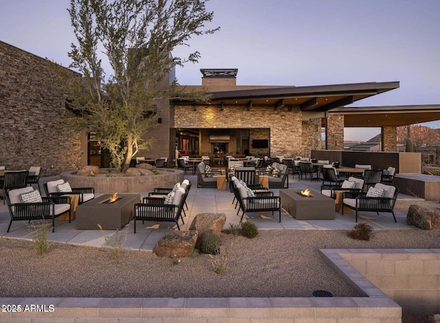 patio terrace at dusk with an outdoor living space with a fire pit