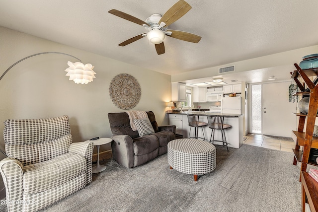 living area with light tile patterned floors, a textured ceiling, visible vents, and light colored carpet