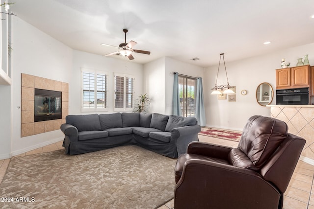 living room featuring ceiling fan, light tile patterned flooring, and a tile fireplace