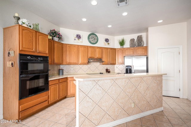 kitchen with black appliances, light tile patterned flooring, a center island with sink, and backsplash