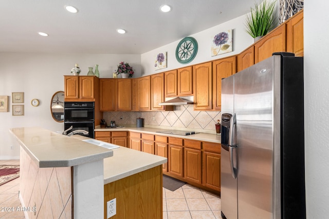 kitchen featuring black appliances, light tile patterned flooring, a kitchen island with sink, and tasteful backsplash