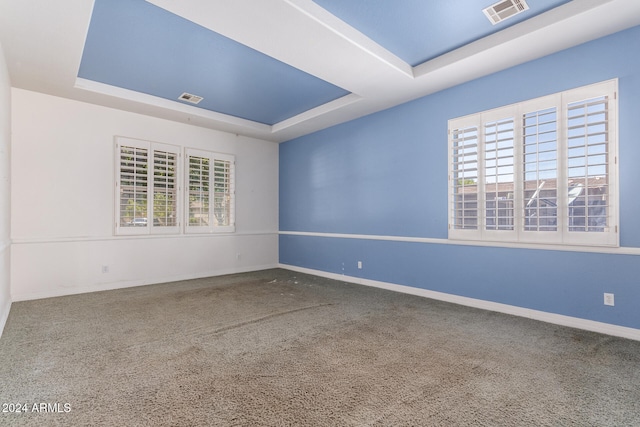 carpeted empty room with a tray ceiling