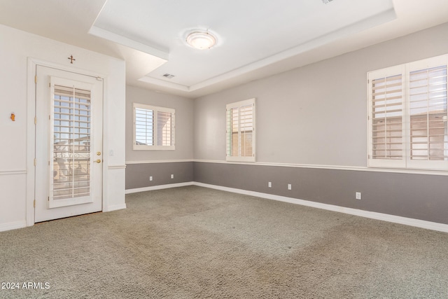 carpeted spare room featuring a tray ceiling