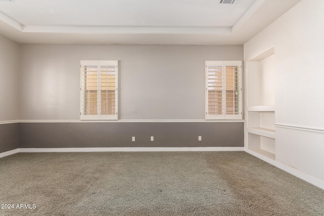 carpeted empty room featuring a tray ceiling