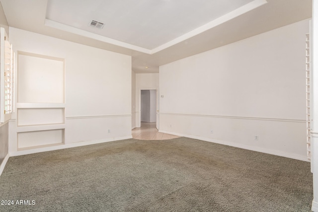 carpeted spare room featuring a tray ceiling