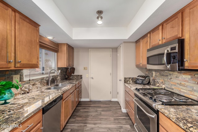 kitchen with decorative backsplash, stainless steel appliances, sink, stone counters, and dark hardwood / wood-style floors