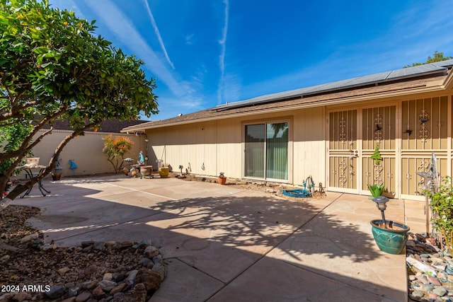 back of property with solar panels and a patio