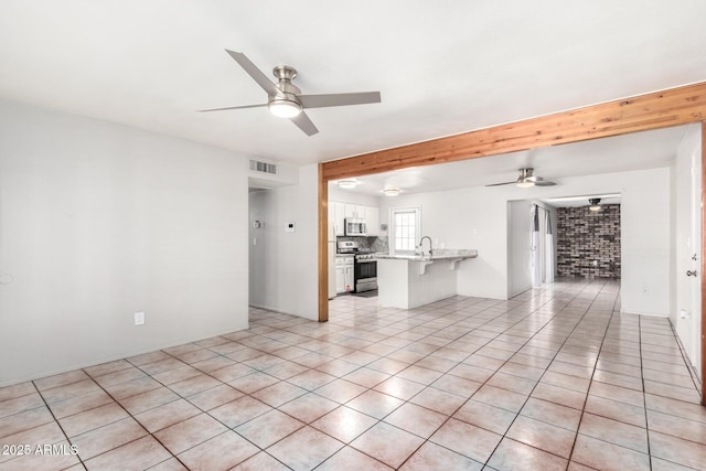 tiled spare room featuring ceiling fan, sink, and brick wall