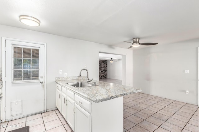 kitchen featuring white cabinets, sink, kitchen peninsula, light stone counters, and light tile patterned floors