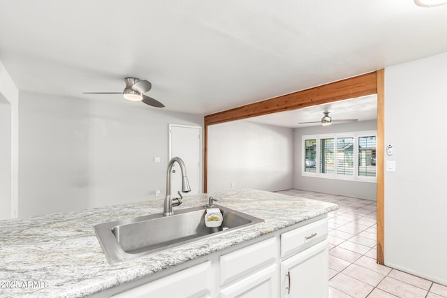 kitchen featuring light tile patterned floors, ceiling fan, white cabinets, light stone counters, and sink