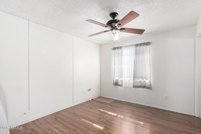 empty room with ceiling fan, dark hardwood / wood-style floors, and a textured ceiling