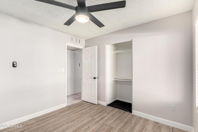 unfurnished bedroom featuring ceiling fan, a textured ceiling, a closet, and light hardwood / wood-style flooring