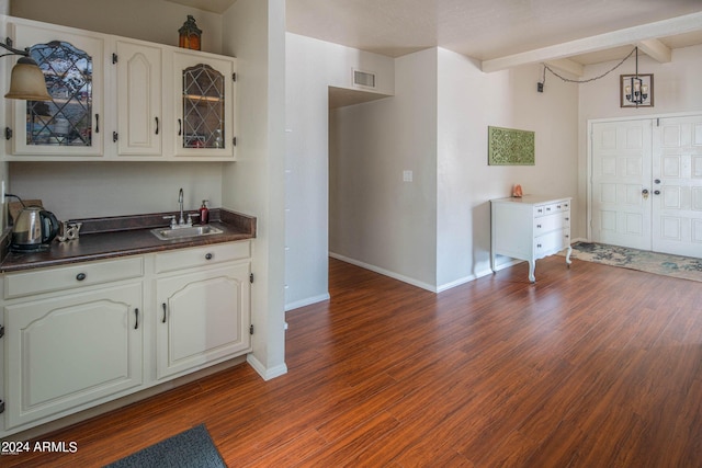 kitchen with beam ceiling, dark hardwood / wood-style flooring, white cabinetry, and sink