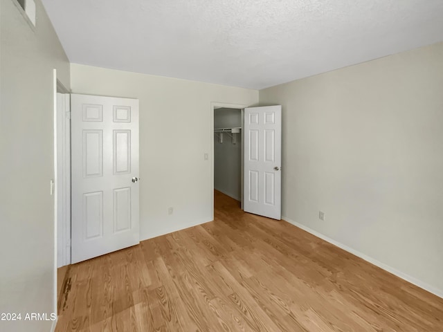 unfurnished bedroom with light hardwood / wood-style floors, a closet, and a textured ceiling