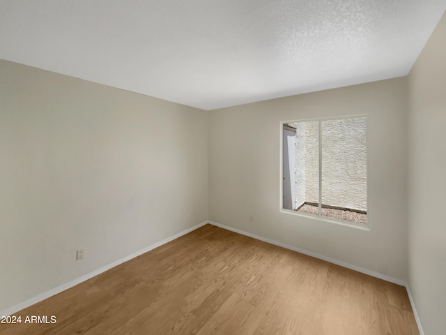 unfurnished room with a textured ceiling and light hardwood / wood-style floors