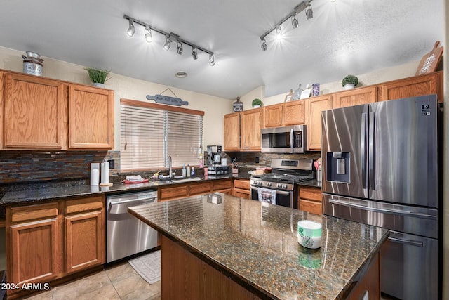 1147 N Marvin St, Gilbert, AZ 85233 - kitchen with stainless steel appliances, a sink, backsplash, rail lighting, and dark stone countertops