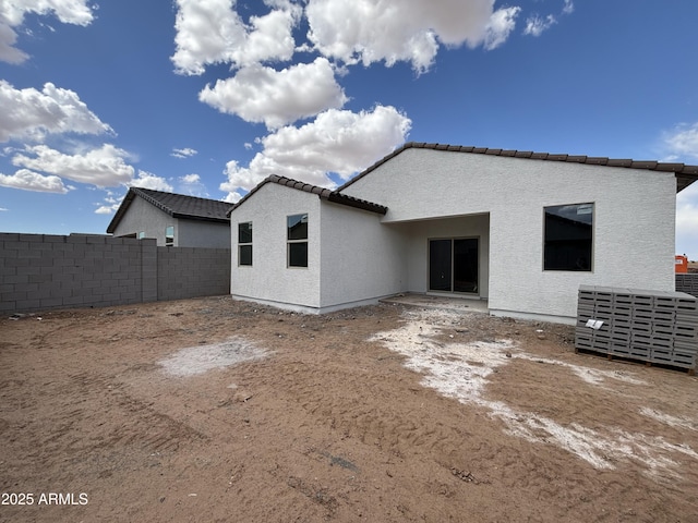 rear view of property with a tiled roof, fence, and stucco siding