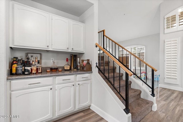 bar with white cabinets, a textured ceiling, and light hardwood / wood-style floors