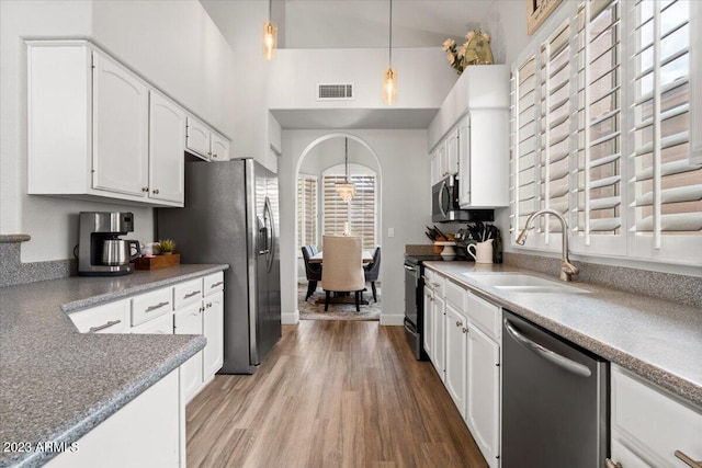 kitchen featuring stainless steel appliances, hardwood / wood-style floors, sink, decorative light fixtures, and white cabinetry