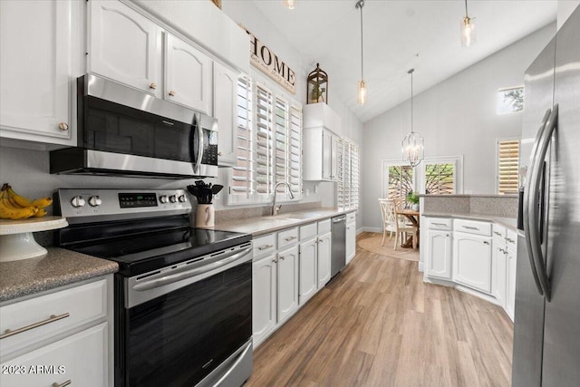 kitchen featuring a healthy amount of sunlight, white cabinets, stainless steel appliances, and hanging light fixtures