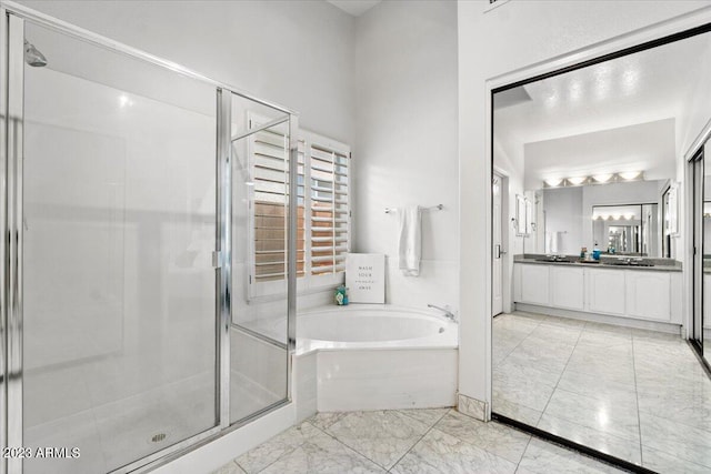 bathroom with vanity and shower with separate bathtub