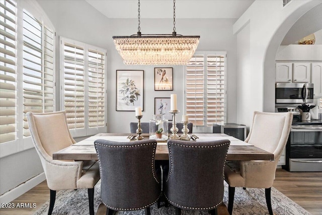 9056 E Maple Dr, Scottsdale, AZ 85255 - dining room with wood finished floors, arched walkways, and a notable chandelier