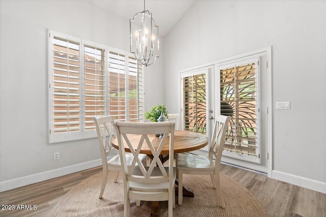 dining area with a notable chandelier, hardwood / wood-style flooring, and high vaulted ceiling