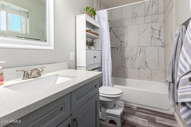 full bathroom featuring shower / tub combo, hardwood / wood-style flooring, vanity, and toilet