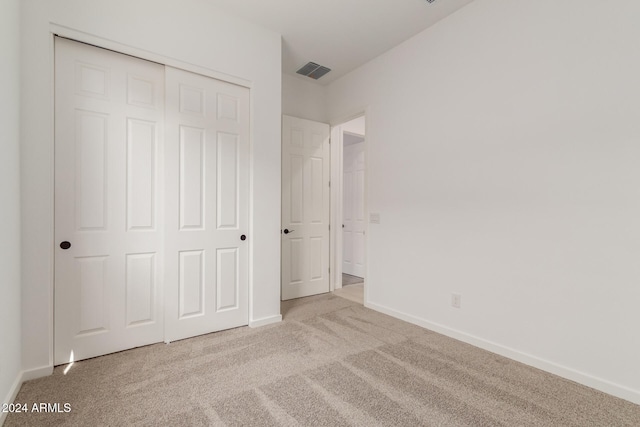 unfurnished bedroom with light carpet and a closet