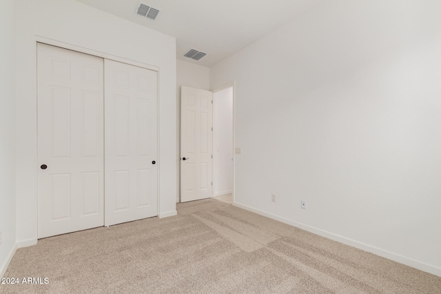 unfurnished bedroom with light carpet and a closet