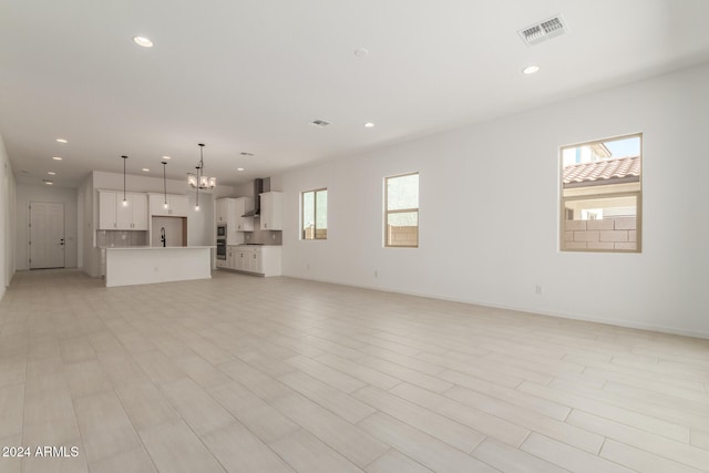 unfurnished living room with a notable chandelier