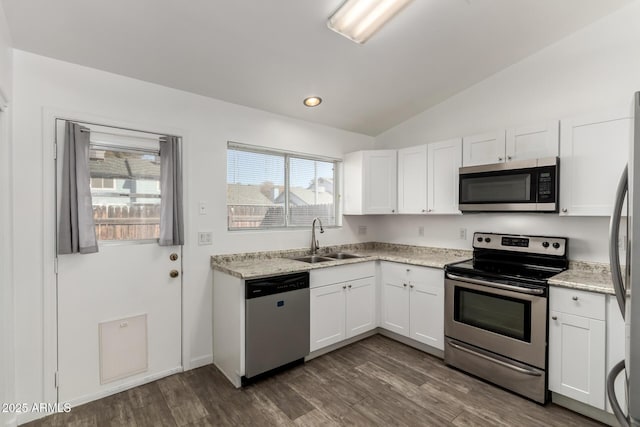 kitchen featuring white cabinets, stainless steel appliances, sink, vaulted ceiling, and light stone counters