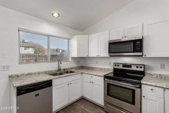 kitchen with appliances with stainless steel finishes, dark wood-type flooring, vaulted ceiling, white cabinets, and sink