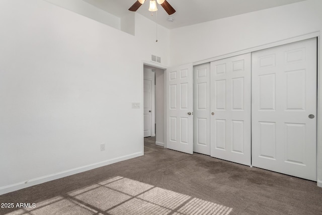 unfurnished bedroom featuring ceiling fan, a closet, a high ceiling, and carpet flooring