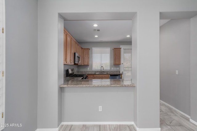 kitchen featuring stone counters, appliances with stainless steel finishes, sink, and kitchen peninsula