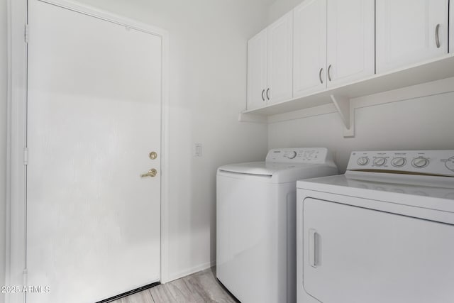 clothes washing area featuring cabinets, independent washer and dryer, and light hardwood / wood-style floors