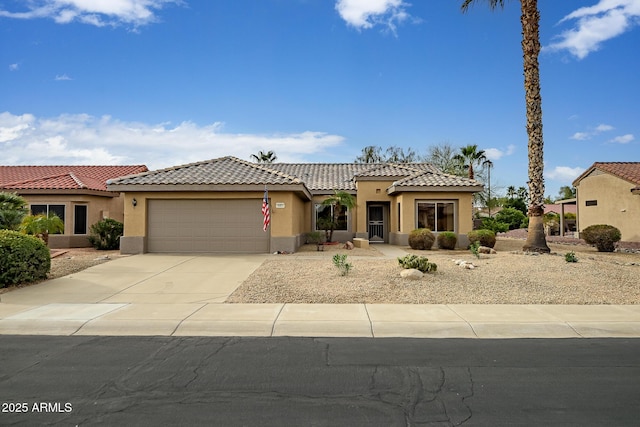 mediterranean / spanish house featuring a garage, driveway, a tile roof, and stucco siding